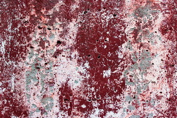 Abstract defective concrete wall with light and red peeling paint