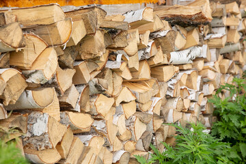 A pile of logs of birch wood stacked neatly along the wall.