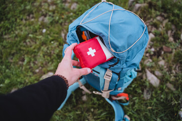 A first aid kit is in a backpack, a hand holds a bag of medicines, an open pocket of a bag, road...