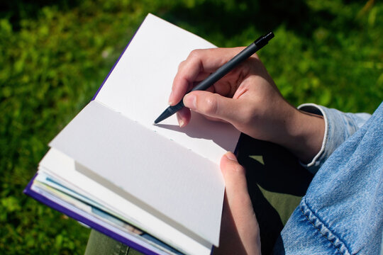 Close up of girl's hands writing and drawing in sketchbook and notepad. Education and study, time back to school.