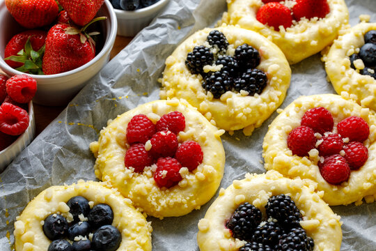 Raw sweet yeast buns with the addition of berry fruit and butter crumble, prepared for baking, close up view