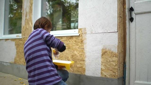Female worker paints the wooden wall of the house. Hand with wall paint roller
