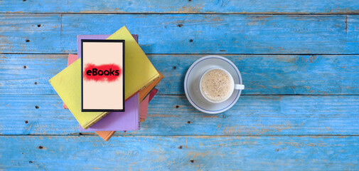 Stack of books, eBook reader and cup of cappuccino coffee, flat lay with good copy space, Reading, literature, relaxing concept.