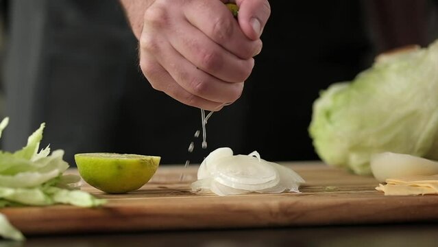 Cooking, the chef squeezes a lime on the table. Slow motion