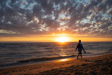 Eine Frau geht im Sonnenuntergang am Strand spazieren