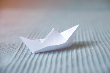 White paper boat on a light blue fabric background 