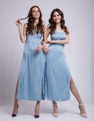 Two fashion models in same looks, outfits. Pretty sky blue dress. Beautiful young woman.  Girls posing on white studio background