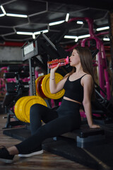 Fototapeta na wymiar Beautiful Sporty Woman Holding Shaker With Water In The Gym