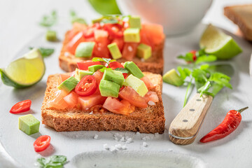 Fototapeta na wymiar Crunchy and delicious toasts with avocado, tomatoes and coriander.