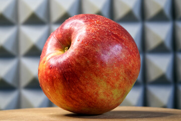 A single large ripe apple on a wooden surface, side view. Apple macro.