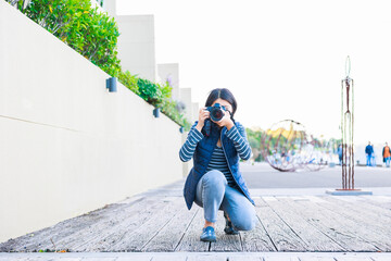 しゃがんで写真を撮る女性フォトグラファー