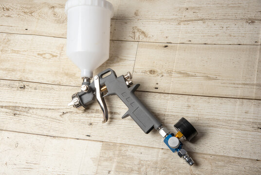 Image of the painter's arm hand holding industrial size spray gun used for industrial painting and coating and isolated on black background