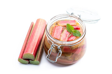 Homemade rhubarb jam in jar with raw stalk rhubarb isolated on white