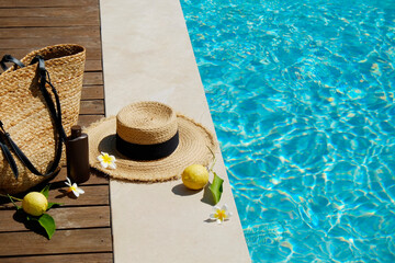 Swimming pool essentials concept. Beach bag with items for safe sunbathing on the deck, sunglasses,...