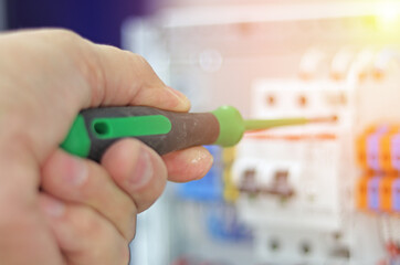 An electrical engineer installs modules in the control panel with a screwdriver.