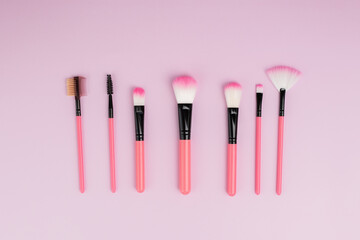 makeup brushes on a pink background, a set of cosmetics for applying powder, blush, foundation