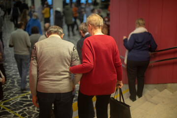 Elderly people leave hall. Old people go to meet veterans. People of older age.
