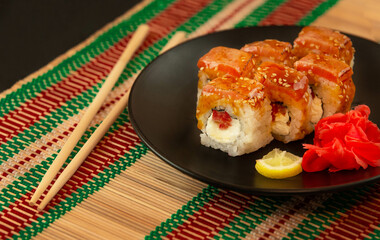 Sushi (rolls) serving on black plate and mat