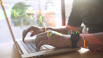 Hand typing input to laptop Overlay investment graphs