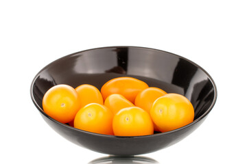 Several ripe yellow tomatoes on a black ceramic plate, close-up, isolated on a white background.