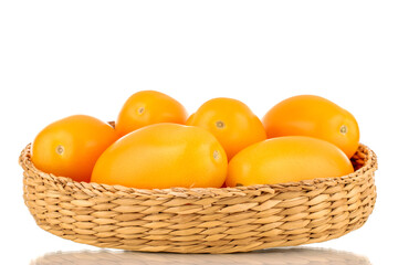 Several ripe yellow tomatoes in a straw dish, close-up, isolated on a white background.