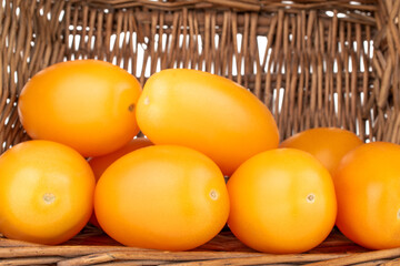 Several ripe yellow tomatoes in a basket, close-up.