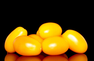 Several ripe yellow tomatoes, close-up, isolated on a black background.