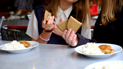Two schoolgirl girls are sitting in the school cafeteria and are going to have lunch.