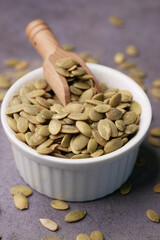  pumpkin seeds in a small bowl on black background 
