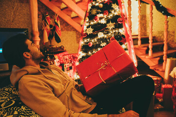 Man sitting near the Christmas tree with a gift