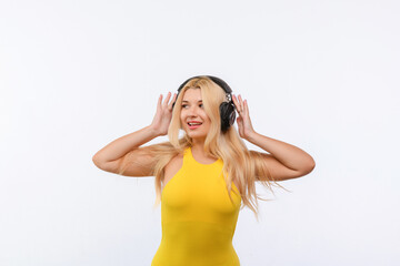Obraz na płótnie Canvas beautiful girl in black headphones and yellow dress listens to music on a white background. different emotions