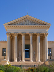 Naklejka premium Vertical view of the neoclassical stone facade with columns and pediment representing Justice of the historic courthouse, a landmark of Montpellier, France