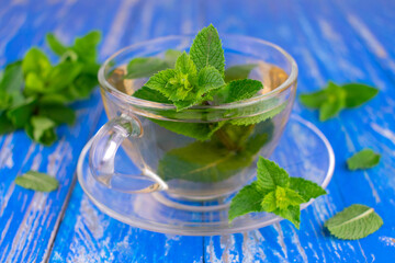 A cup of soothing mint tea on a wooden blue background.