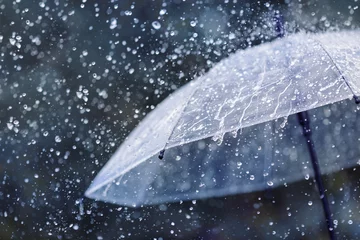 Foto op Canvas Transparent umbrella under heavy rain against water drops splash background. Rainy weather concept. © juliasudnitskaya