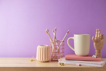 Fototapeta Stylish feminine table with coffee cup, notebook and pencils over purple background. Back to school concept obraz