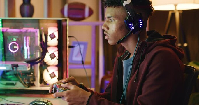 Gamer getting upset while playing video games on a computer at night. Angry and annoyed esports player throwing a controller and banging fists after losing competition in a multiplayer session online