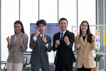 Obraz premium Asian business team celebrate corporate victory together in office, laughing and rejoicing, smiling excited employees colleagues screaming with joy in office.