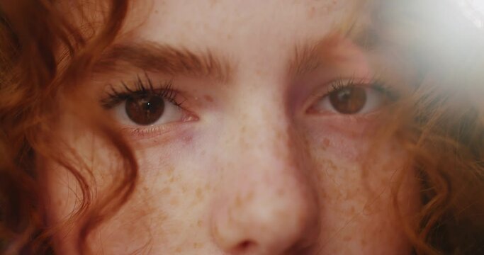Portrait eyes sunshine young smiling woman with red curly hair look at camera. Feel happy. Summer. Outdoors at sunlight. Slow motion