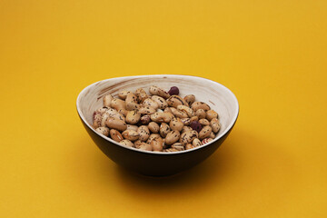 Bean seeds in a plate on an orange background. Close-up