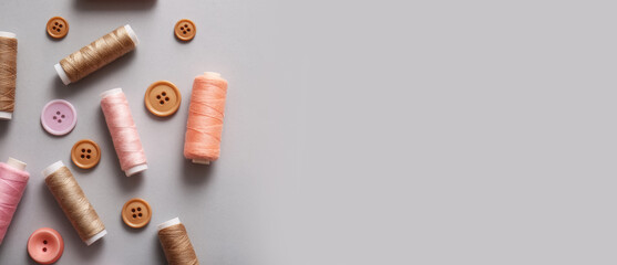 Sewing threads and buttons on grey background with space for text