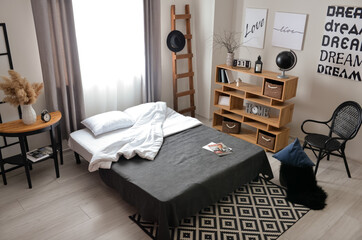 Interior of stylish bedroom with ladder and shelving unit