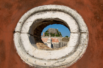 View of Venetian Fortress on hill via a decorative wall hole at Corfu Greece