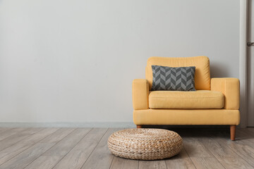 Comfortable yellow armchair near light wall in room