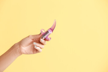 Female hand with vibrating bullet from sex shop on color background