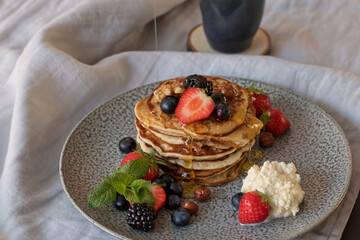 Syrup drizzled pancakes with fruit, mint and cream