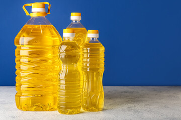 Bottles of sunflower oil on table against blue background