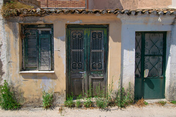 Fototapeta na wymiar Green rotten wooden window and doors at old abandoned stone house at Corfu Greece