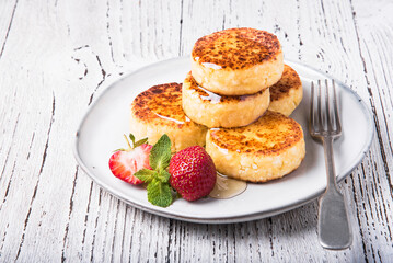 Cheesecakes with strawberries and honey on a white table.