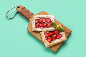 Wooden board with delicious strawberry puff pastry on color background
