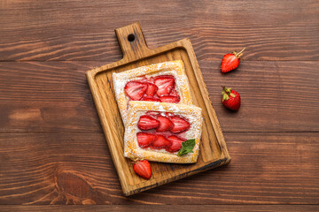 Board with delicious strawberry puff pastry on wooden background